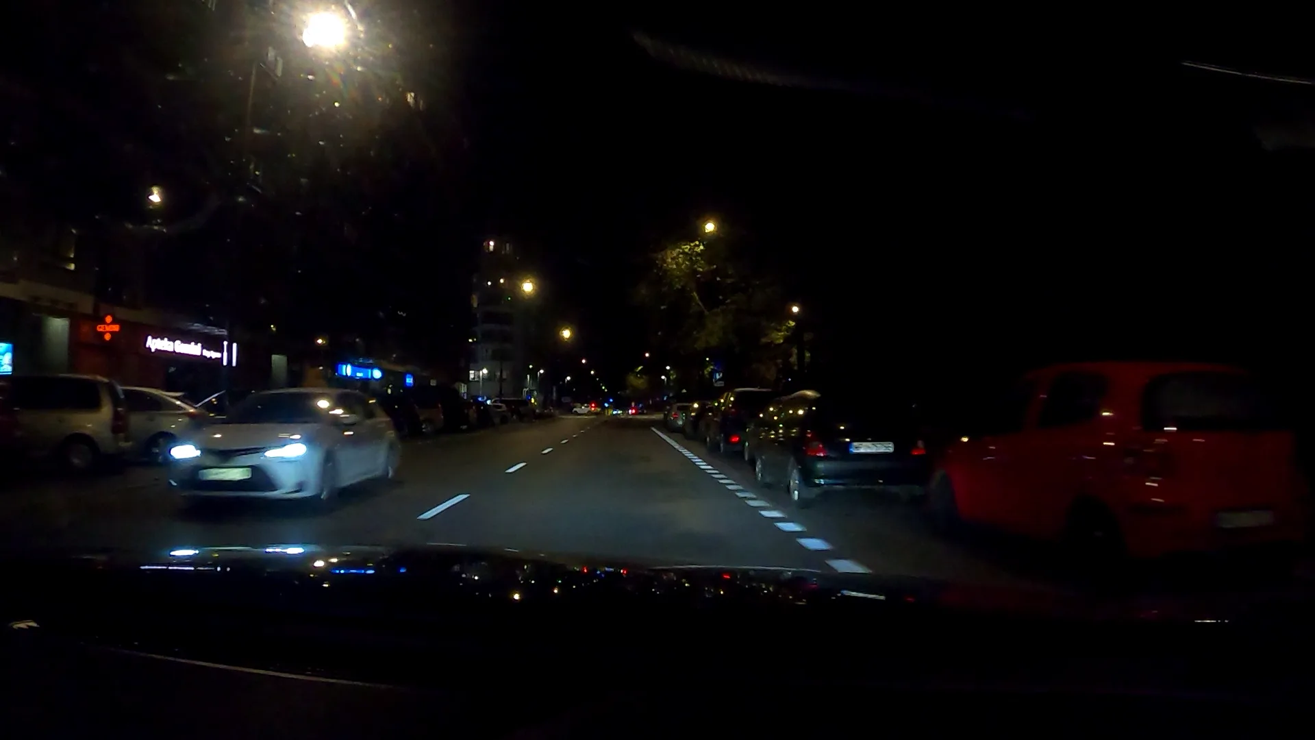 Nighttime recording in motion with lamp reflections and illegible signs