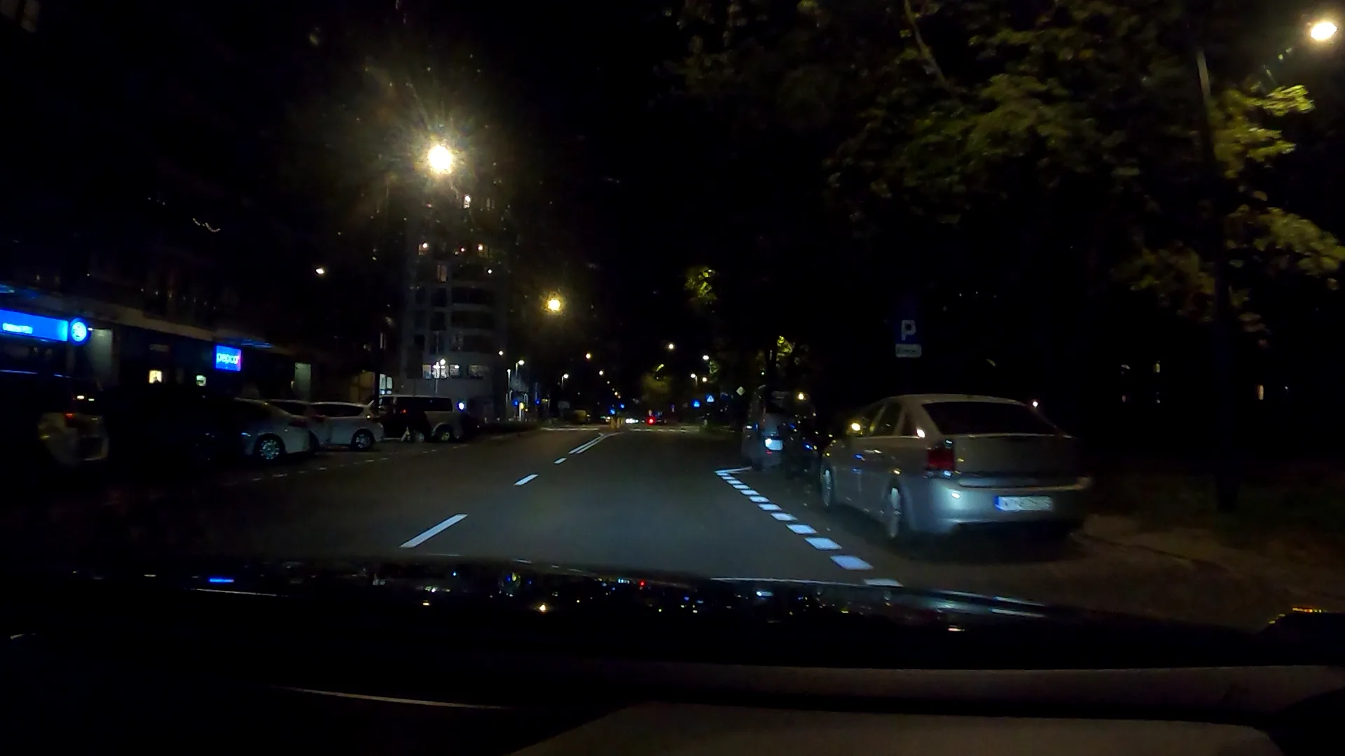 Night shot of parked vehicles; the image of the boards is too detailed for reliable reading